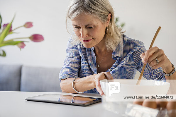Caucasian woman baking with recipe on digital tablet