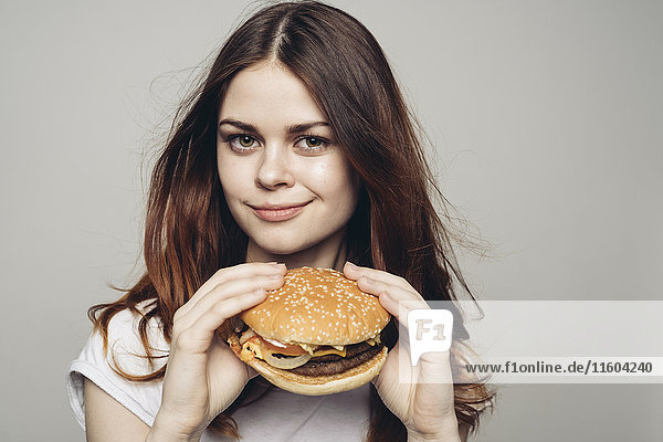 Grinning Caucasian woman holding cheeseburger