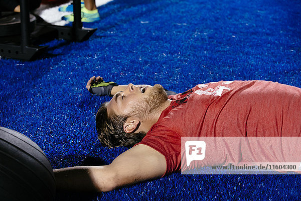 Fatigued Caucasian man laying on sports field