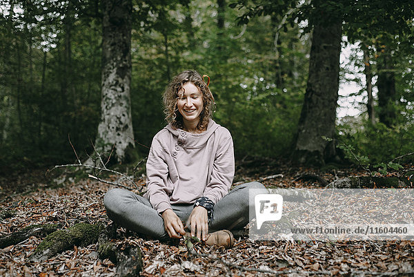 Caucasian woman sitting in autumn leaves in forest