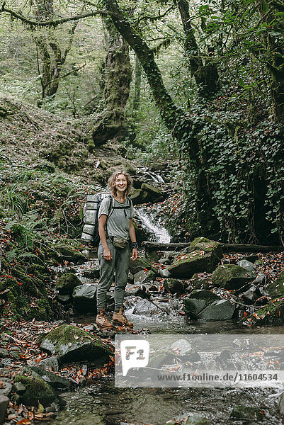 Caucasian woman backpacking across forest stream