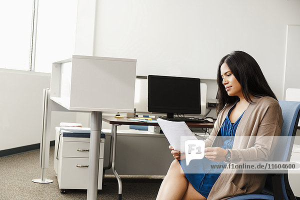 Pacific Islander woman reading paperwork in office