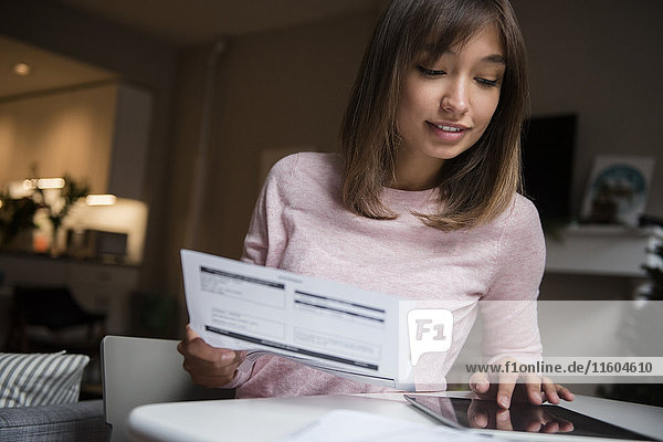 Mixed-Race-Frau bezahlt Rechnungen auf digitalem Tablet