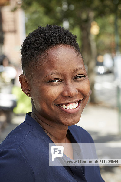 Schwarze Frau lächelt auf dem Bürgersteig der Stadt