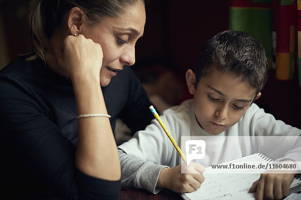 Hispanische Mutter beobachtet ihren Sohn beim Schreiben des Alphabets