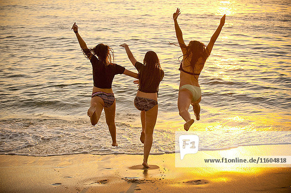 Teenager-Mädchen laufen bei Sonnenuntergang ins Meer