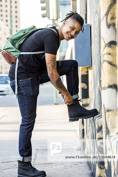 Androgynous Mixed Race woman carrying backpack adjusting boot