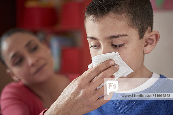 Hispanische Mutter wischt die Nase ihres Sohnes mit einem Taschentuch ab