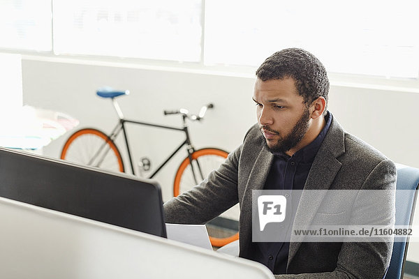 Gemischtrassiger Mann mit Computer im Büro