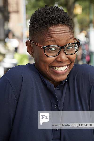 Porträt einer schwarzen Frau  die auf dem Bürgersteig mit den Schultern zuckt