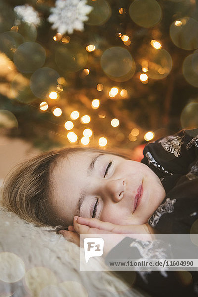 Caucasian girl sleeping near Christmas tree