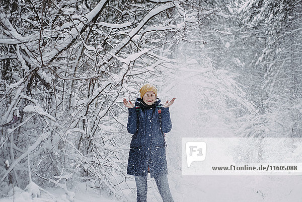 Schnee fällt auf eine kaukasische Frau im Wald
