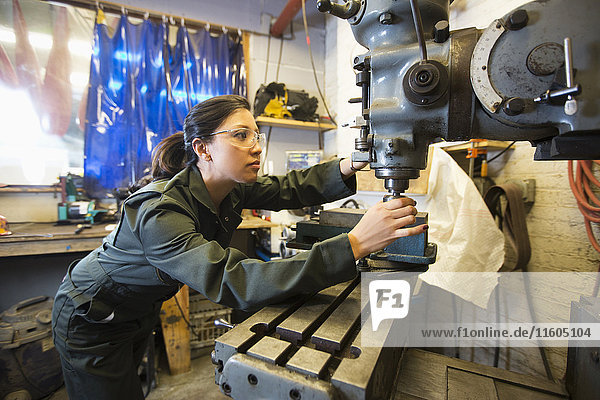 Gemischtrassige Frau benutzt Maschinen in einer Werkstatt