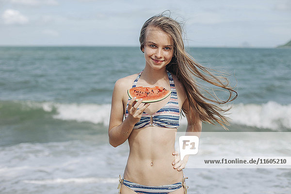 Kaukasische Frau isst Wassermelone am Strand