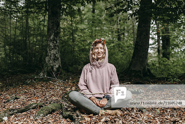 Kaukasische Frau sitzt mit Herbstblättern in der Kapuze