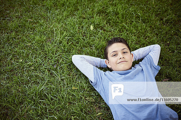 Smiling Hispanic boy laying in grass