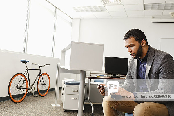 Mann mit gemischter Hautfarbe benutzt digitales Tablet im Büro