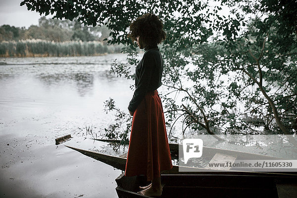 Kaukasische Frau steht in einem Boot am Fluss