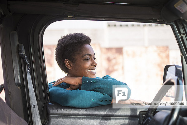Lächelnde afroamerikanische Frau  die sich an ein Autofenster lehnt