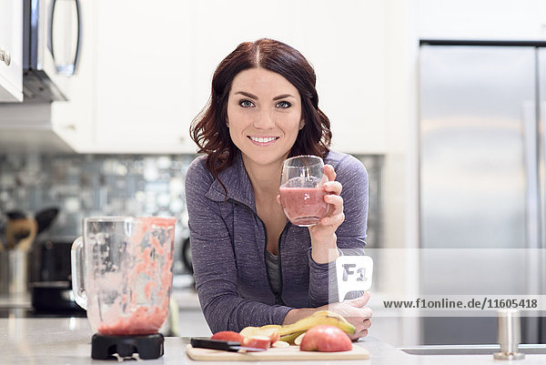 Caucasian woman drinking fruit smoothie in domestic kitchen