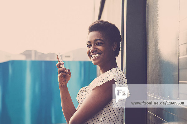 Lächelnde afroamerikanische Frau mit Mobiltelefon in der Hand