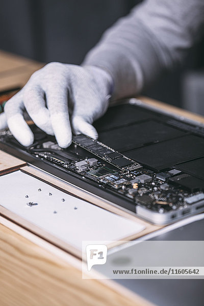 Detailbild eines Technikers bei der Reparatur eines digitalen Tabletts im Elektronikgeschäft