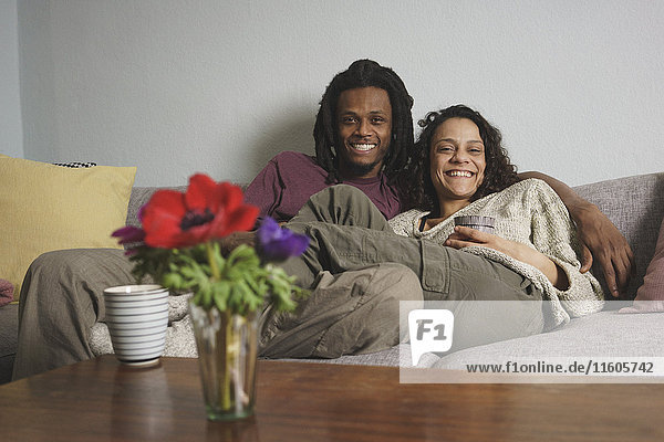 Porträt eines glücklichen multiethnischen Paares auf dem Sofa zu Hause