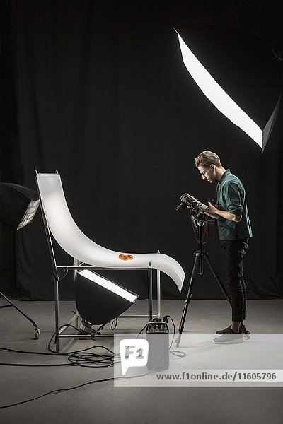 Seitenansicht des Fotografen beim Fotografieren von Lebensmitteln im Studio