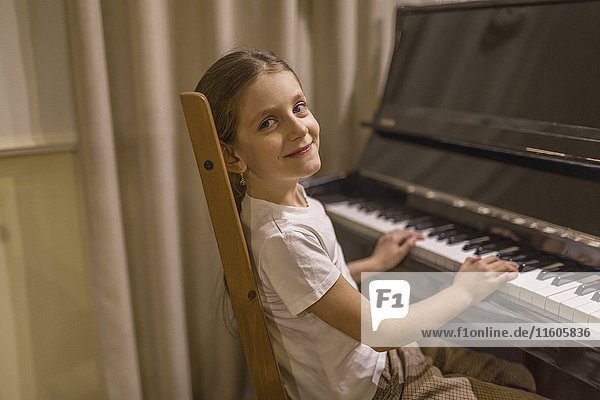 Side view portrait of cute girl playing piano at home