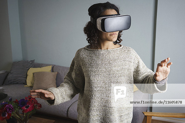 Frau mit Virtual-Reality-Headset im Stehen im Wohnzimmer