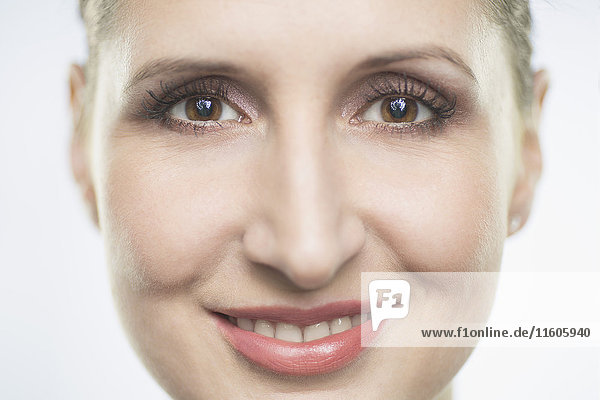Nahaufnahme Porträt einer lächelnden erwachsenen Frau vor weißem Hintergrund