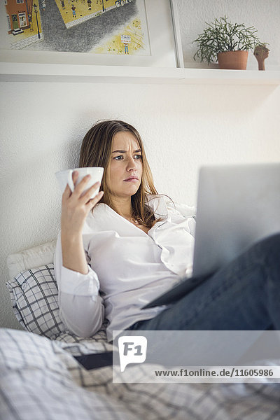 Young woman using laptop in bed