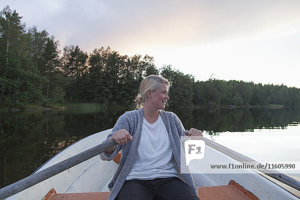 Happy woman rowing boat on lake against sky