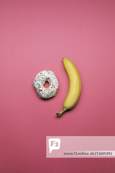 Donut und Banane auf rosa Hintergrund