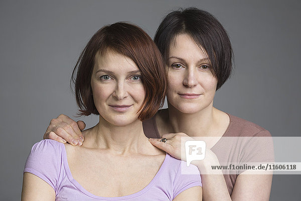 Portrait of confident mature women against gray background