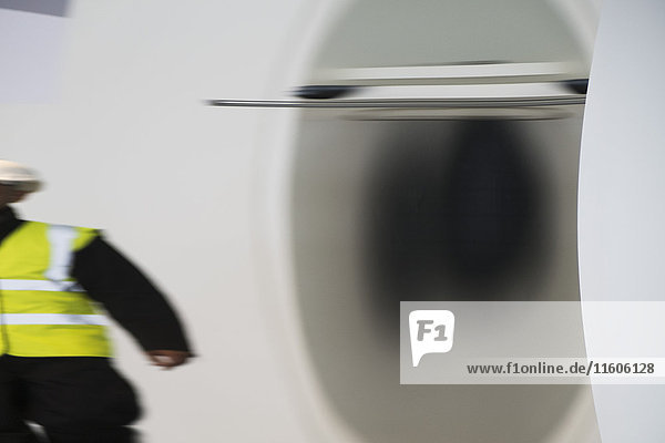 Defokussiertes Bild eines Bauarbeiters  der an einer metallischen Anlage steht.