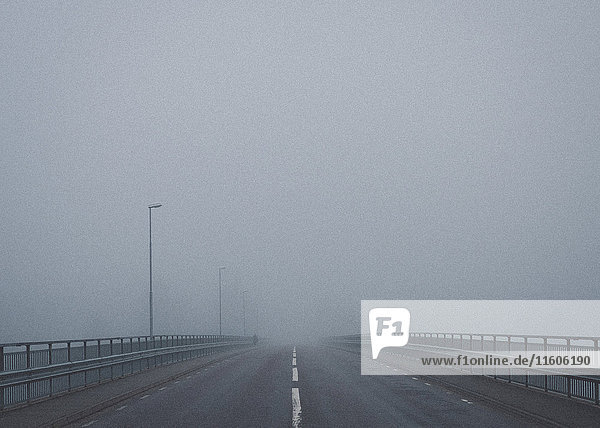 Straße auf der Brücke gegen den Himmel bei nebligem Wetter