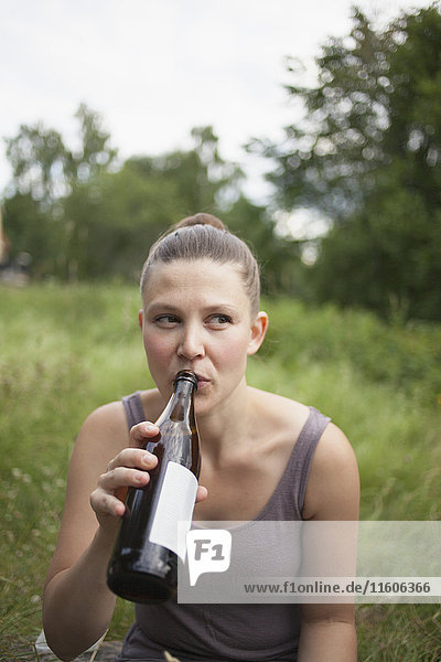 Mittlere erwachsene Frau schaut weg  während sie auf dem Feld Wein trinkt.