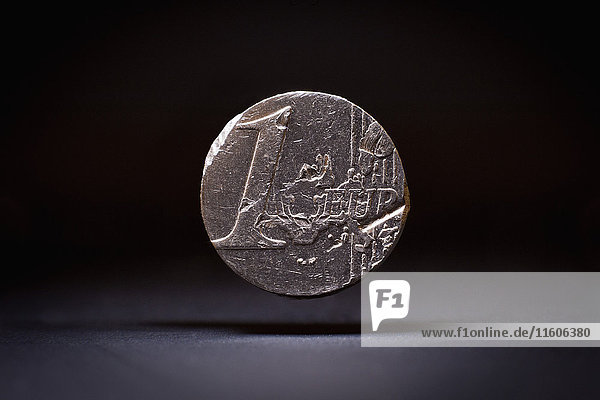 Nahaufnahme einer beschädigten Euro-Münze auf schwarzem Hintergrund
