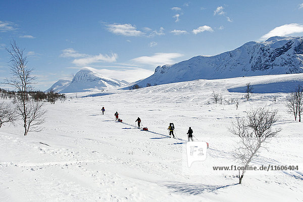 Tourists cross country skiing against mountain scenery