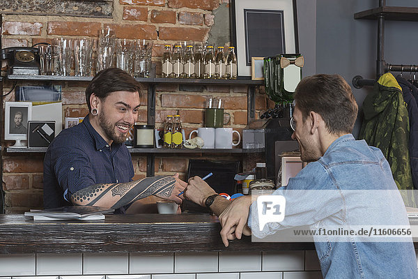 Cheerful male barbers sitting at bar counter in hair salon