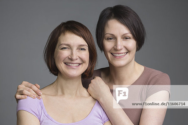 Portrait of happy mature female friends against gray background