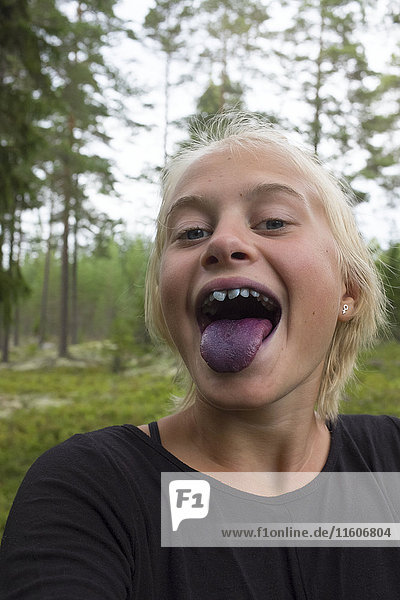 Mädchen mit blauer Zunge nach dem Verzehr von Beeren