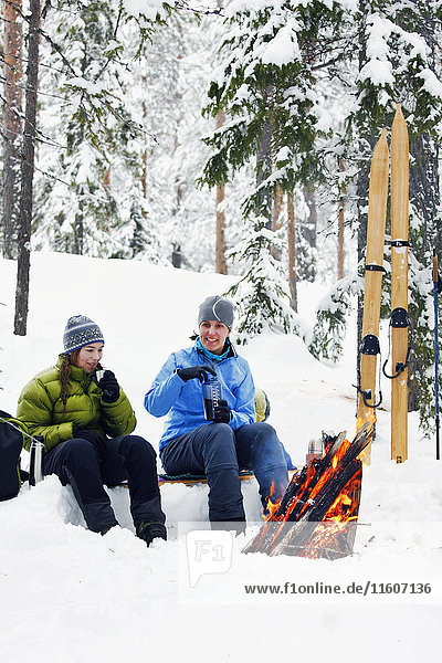 Frauen ruhen sich am Kamin im Winterwald aus