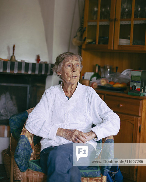 Thoughtful senior woman sitting on armchair at home