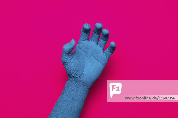 Nahaufnahme der blau bemalten Hand auf rosa Hintergrund