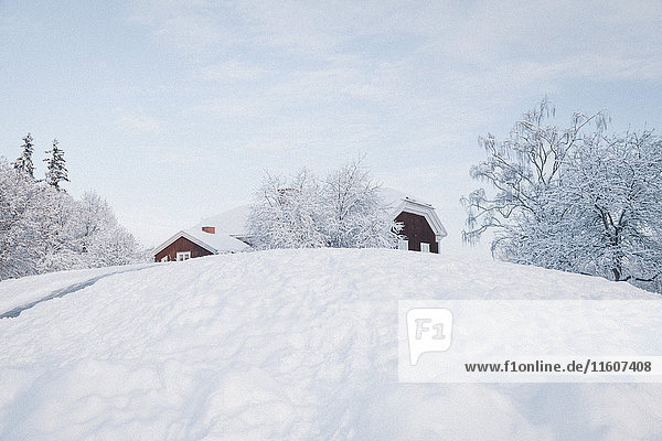 Flachwinkelansicht von Häusern auf schneebedecktem Hügel gegen den Himmel