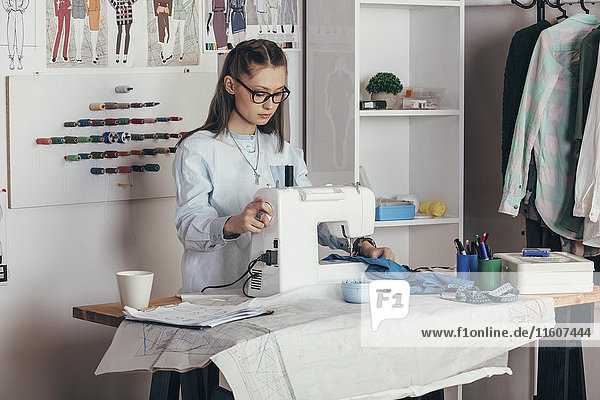 Female fashion designer using sewing machine at design studio