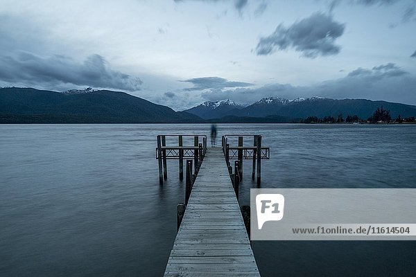 Cloudy sky over mountains  silhouette standing on dock  Lake Te Anau  Southland  New Zealand  Oceania