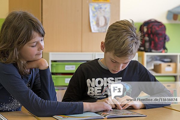 Students  children reading a book together  classroom  elementary school  Lower Saxony  Germany  Europe